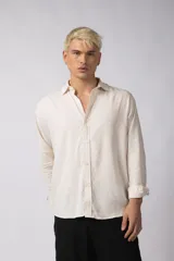 Camisa de manga larga con cuello clásico y cierre frontal de botones. Presenta un calce relajado y una textura liviana.