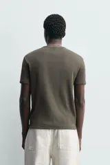 Camiseta de corte regular con cuello redondo y manga corta, confeccionada en tejido con acabado en rib.