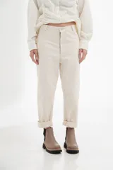 Pantalón color crudo, de corte recto, con bolsillos frontales y traseros, costuras contrastantes y cierre frontal.