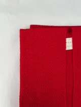 Ruana tejida en baby alpaca de color rojo tomate, con textura liviana y corte recto de caída fluida.