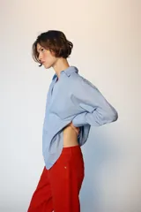 Camisa de manga larga en color celeste con estampado de rayas finas, cuello solapa y escote en pico con detalle de solapa frontal. Presenta puños abotonados y bajo asimétrico.