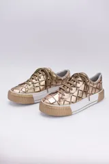 Zapatillas bajas color dorado con diseño trenzado, cordones y suela de goma.