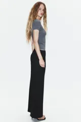 Pantalón de tiro bajo y corte recto, color marrón oscuro. Presenta bolsillos laterales, cierre frontal con cremallera y gancho metálico, y un cinturón integrado del mismo tejido con hebilla metálica.