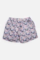 Short de baño celeste con estampado de hojas pequeñas en tonos verdes y blancos. Cuenta con cintura elástica con cordón ajustable, bolsillos laterales y un parche circular con logo en la parte inferior.
