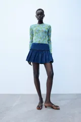 Jersey de punto Zara con cuello redondo y manga larga, con estampado floral a contraste en tonos verdes y morados sobre base celeste.