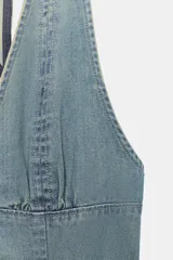 Vestido corto de denim con escote halter y cuello en pico, tirantes cruzados para atar en el cuello y falda acampanada con pliegues.