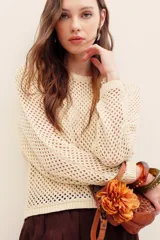 Sweater de punto calado color beige con hilos de lurex, de corte recto, manga larga y cuello redondo con terminación elástica acanalada.