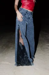 Jean de corte recto y tiro medio en denim color gris oscuro, con diseño de aberturas laterales en las piernas que dejan al descubierto apliques de encaje negro con lentejuelas.