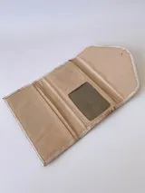 Billetera de cuero con textura rústica y acabado desgastado, presenta un diseño de solapa triangular con un detalle bordado en forma de espiga en el centro.