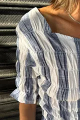 Remera negra de algodón con textura fruncida en todo el cuerpo y mangas cortas con terminación de volado.