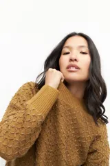 Sweater de tejido texturizado en color beige, con cuello redondo y mangas largas.