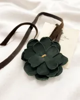 Gargantilla con dije de flor de cuero color verde oscuro y tira de cuero marrón.