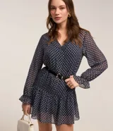 Vestido corto azul marino con estampado de flores blancas y rojas, escote en V, mangas largas con puños elásticos y falda con volantes. Incluye cinturón negro con hebilla dorada.