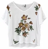 Blusa blanca de manga corta con cuello en V, corte holgado y diseño estampado de flores marrones y hojas verdes en el centro y los hombros.