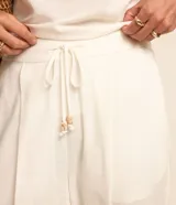 Pantalón fluido Marfinno modelo pijama, color blanco, confeccionado en viscolino. Cuenta con cintura elástica en la espalda, lazo de ajuste, pliegues frontales y bolsillos laterales.