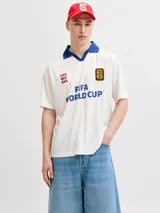 Camiseta de manga corta con cuello tipo polo en color azul, cuerpo en color blanco y calce relajado. Presenta estampados frontales con la leyenda 'FIFA WORLD CUP' y 'CAN MEX USA', junto con un parche conmemorativo del evento.