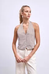 Chaleco con estampado de rayas verticales marrones y blancas, con cuello halter y cierre frontal con botones.