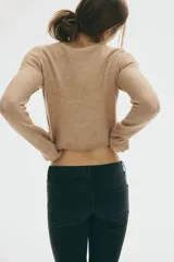 Saco corto de punto jacquard color beige, con estampado de rombos blancos y negros. Tiene cuello redondo, botonadura frontal y ribetes acanalados en puños y bajo.