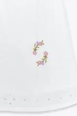 Shorts blancos con cintura elástica, bolsillos laterales ocultos y forro interior. Presenta bordados de flores en tonos rosados y amarillos.