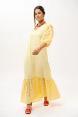 Vestido largo amarillo mantequilla con escote en V, mangas abullonadas y volados en el bajo con detalles de broderie.