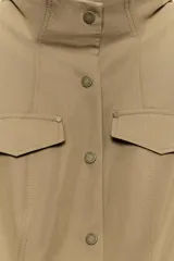 Cazadora de estilo militar en color tostado, con cuello subido, cierre frontal con botones y múltiples bolsillos con solapa en el pecho y la cintura. Cuenta con mangas largas con trabillas en los hombros.