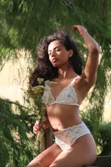 Bralette de encaje blanco con diseño floral, copas triangulares y tirantes elásticos ajustables.