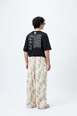 Pantalón cargo baggy color beige con estampado abstracto en tonos grises. Cuenta con bolsillos laterales y cordones ajustables en los tobillos.