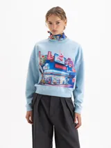 Buzo de cuello redondo y mangas largas, con silueta amplia y largo a la cadera. Presenta un estampado gráfico frontal de estilo urbano con temática de mercado y un conejo, parte de una colaboración artística.