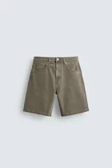 Bermuda de denim de algodón, color verde oliva desgastado, de corte recto y tiro medio. Presenta cinco bolsillos y cierre frontal con cremallera y botón.