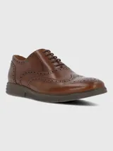Zapato de vestir tipo Oxford o Brogue, color marrón cuero, con puntera y laterales decorados con perforaciones (broguing). Posee cordones y una suela de goma gruesa y moderna de color marrón oscuro.