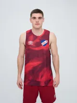 Musculosa deportiva Umbro del Club Nacional de Football, de color rojo con un estampado abstracto en tonos más oscuros. Presenta el logo de Umbro en el pecho derecho y el escudo del club en el pecho izquierdo.