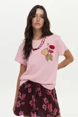 Remera de algodón color rosado, de manga corta, con cuello redondo y detalle de estampa y bordado frontal con diseño de una flor y una higuera.
