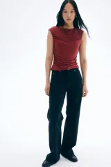 Top ajustado de punto color vino tinto, con escote bote, manga japonesa corta y fruncidos laterales que generan un efecto drapeado.