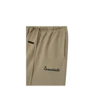 Short de felpa estilo deportivo color beige con cintura elástica con cordón ajustable largo, bolsillos laterales y el logo "Essentials" impreso en la pierna izquierda.