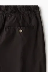 Short de popelina de algodón en color marrón oscuro, con cintura elástica, cierre frontal con botón, bolsillos laterales al bies y bolsillos traseros insertados con botón.