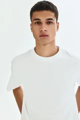 Remera de punto de algodón de peso medio, color blanco, con cuello redondo ribeteado, hombros caídos, bajo recto y corte relajado.