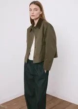 Chaqueta verde militar corta con cuello camisero de pana marrón oscuro, cierre frontal de botones, bolsillos aplicados en el pecho y diseño holgado.