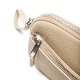 Sobre de mano marca XL, color beige, con textura granulada, cierre principal, bolsillo frontal con cierre y correa de muñeca extraíble.