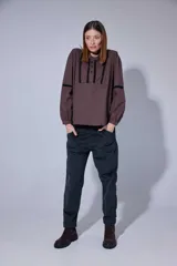 Pantalón de corte recto y tiro medio, confeccionado en tejido con patrón de cuadros oscuros. Presenta bolsillos frontales amplios y terminación con dobladillo en los tobillos.