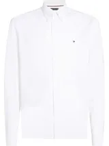 Camisa blanca de corte slim fit, confeccionada en tejido dobby de puro algodón con tecnología Flex que ofrece elasticidad en cuatro direcciones. Tiene cuello abotonado, logo de Tommy Hilfiger bordado en el pecho y cinta distintiva en el interior del cuello.