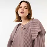 Blusa fluida de manga larga con diseño a rayas en tonos marrón y blanco, con escote redondo adornado con una pequeña abertura y tiras para anudar, y un gran volante superpuesto en los hombros.