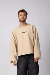 Buzo de cuello redondo confeccionado en tejido rústico con bordes al corte y costuras expuestas. Presenta un diseño boxy con estampado frontal y es reversible, permitiendo su uso por ambos lados.