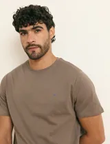 Remera básica de algodón color beige, de manga corta, con cuello redondo y un pequeño detalle bordado en el pecho.
