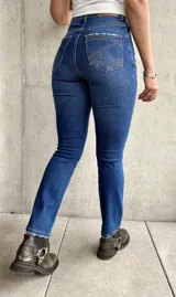 Jean de calce recto con lycra, color azul medio, con bolsillos delanteros y traseros.