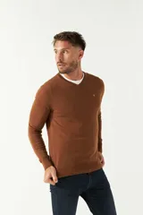 Sweater de punto color negro con escote en V, manga larga y puños acanalados. Presenta un pequeño logo bordado en el pecho.