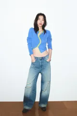 Chaqueta de punto color azul, con cuello redondo y manga larga. Presenta acabados en contraste de color verde neón y cierre frontal cruzado con botones.