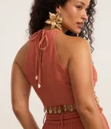 Blusa color ladrillo con escote halter, sin mangas, lazo en la espalda y flecos con caracolas en la cintura.