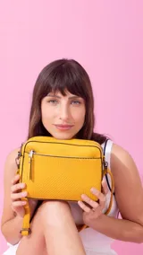 Bandolera color bordó con diseño texturizado geométrico en el frente, bolsillo frontal con cierre, bolsillo trasero con cierre y compartimento principal con divisiones. Incluye correa extensible.