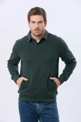 Buzo de felpa color verde oscuro, con cuello tipo polo, cierre frontal parcial con botones y bolsillos laterales. Presenta puños y ruedo acanalados.