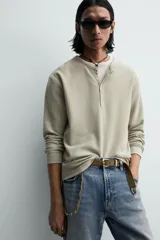 Camiseta de manga larga para hombre con corte relajado, confeccionada en tejido con estructura waffle. Presenta un cuello redondo tipo panadero con cierre frontal de botones a presión.